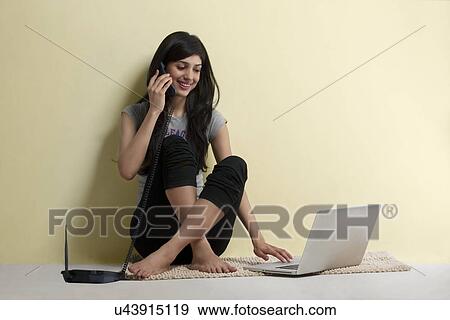 Young girl with a laptop talking on a phone View Large Photo Image Stock Photo - Young girl with a laptop talking on a phone . Fotosearch