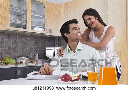 Stock Photo - Young Indian couple spending leisure time in kitchen. Fotosearch