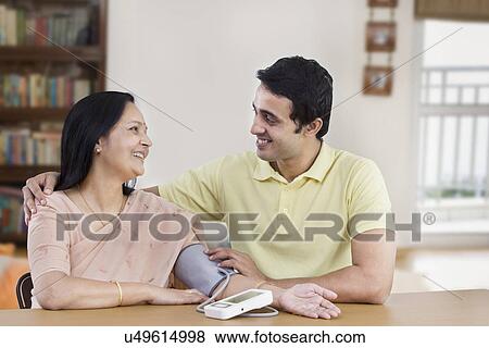 Young man checking mother's blood pressure View Large Photo Image Stock Photo - Young man checking mother's blood pressure . Fotosearch