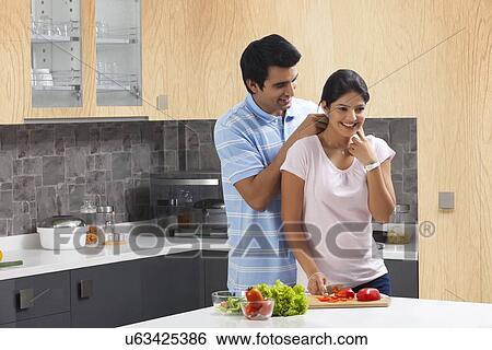 Young man fastening woman's necklace in kitchen View Large Photo Image Stock Photograph - Young man fastening woman's necklace in kitchen. Fotosearch