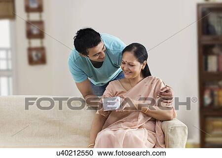 Young man giving gift to his smiling mother View Large Photo Image Stock Image - Young man giving gift to his smiling mother . Fotosearch