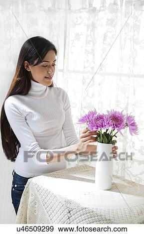 Stock Photo - Young woman arranging flowers in a vase . Fotosearch