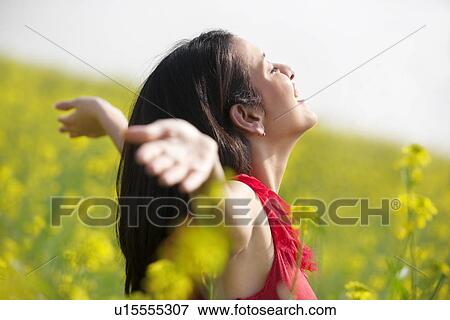 Stock Photo - Young woman enjoying herself in a field . Fotosearch