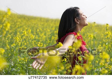 Stock Photography - Young woman enjoying herself in a field . Fotosearch