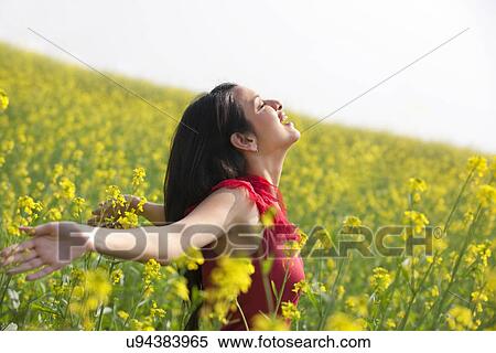 Stock Photography - Young woman enjoying herself in a field . Fotosearch