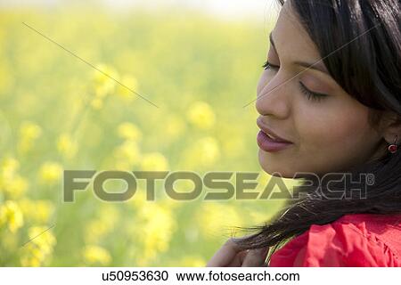 Stock Image - Young woman enjoying in a field . Fotosearch