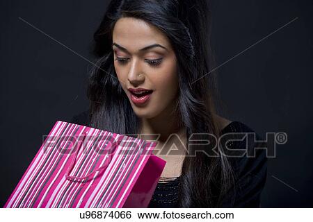 Young woman looking inside a shopping bag View Large Photo Image Stock Photograph - Young woman looking inside a shopping bag . Fotosearch