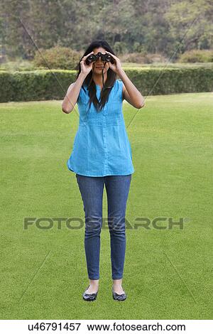 Stock Photo - Young woman looking through binoculars . Fotosearch
