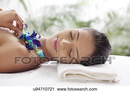 Young woman on massage table holding flower View Large Photo Image Stock Image - Young woman on massage table holding flower . Fotosearch