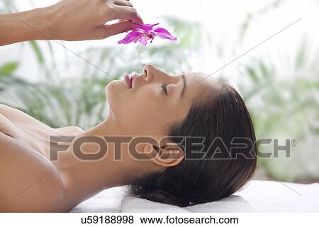 Young woman on massage table smelling flower View Large Photo Image Stock Photo - Young woman on massage table smelling flower . Fotosearch