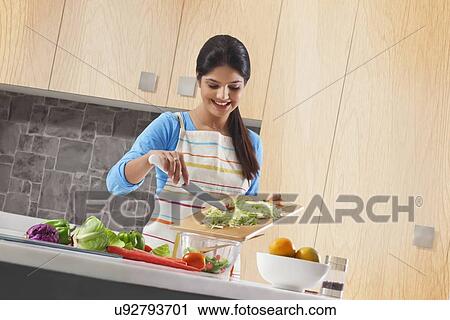 Young woman preparing fresh vegetable salad in kitchen View Large Photo Image Stock Image - Young woman preparing fresh vegetable salad in kitchen. Fotosearch