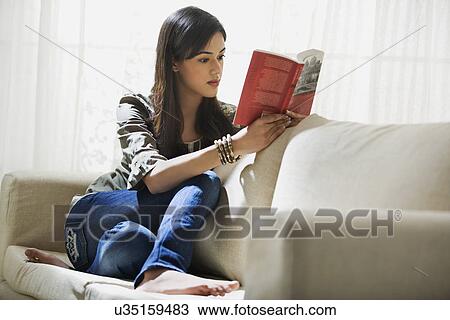 Young woman reading a book on a sofa View Large Photo Image Stock Image - Young woman reading a book on a sofa . Fotosearch