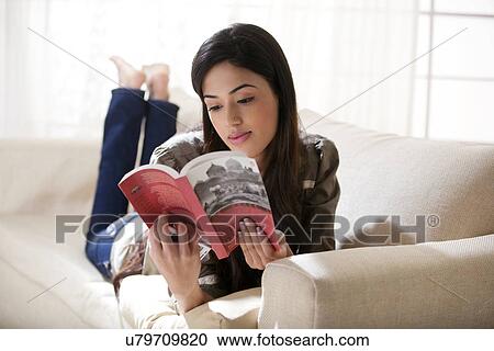 Young woman reading a book on a sofa View Large Photo Image Stock Image - Young woman reading a book on a sofa . Fotosearch