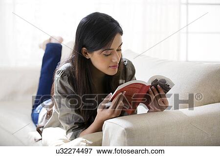 Young woman reading a book on a sofa View Large Photo Image Stock Photo - Young woman reading a book on a sofa . Fotosearch