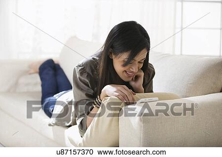 Stock Image - Young woman watching a video on her mobile phone . Fotosearch