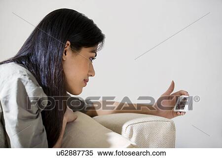 Young woman watching a video on her mobile phone View Large Photo Image Stock Photography - Young woman watching a video on her mobile phone . Fotosearch