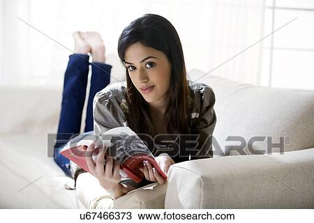 Stock Image - Young woman with a book on a sofa . Fotosearch