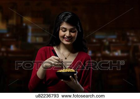 Stock Image - Young woman with a bowl of noodles . Fotosearch
