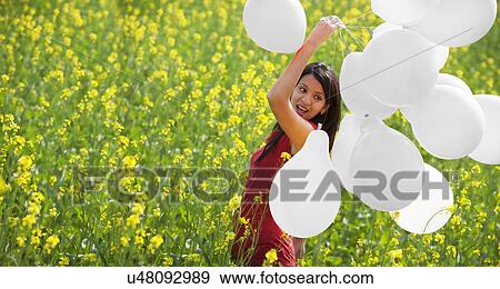 Young woman with balloons in a field View Large Photo Image Stock Photo - Young woman with balloons in a field . Fotosearch