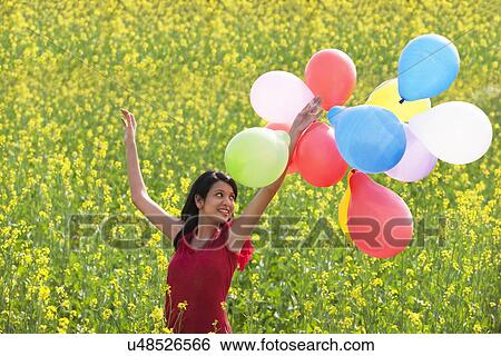Young woman with balloons in a field View Large Photo Image Stock Photograph - Young woman with balloons in a field . Fotosearch