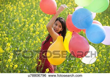 Stock Photograph - Young woman with balloons in a field . Fotosearch
