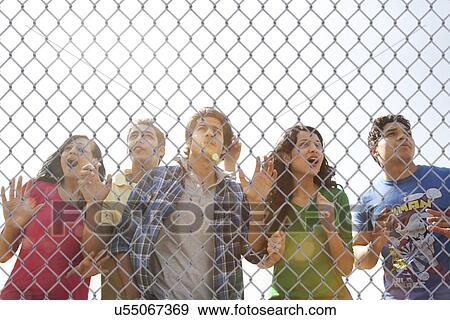 Youngsters watching a match through a wire mesh View Large Photo Image Stock Photo - Youngsters watching a match through a wire mesh . Fotosearch