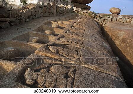 Stock Photo - Carved Nandi figures and Shivalingas on a rocky surface . Fotosearch