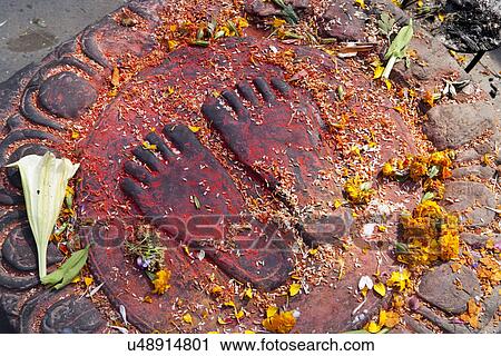 Stock Image - Footprints decorated with offerings . Fotosearch