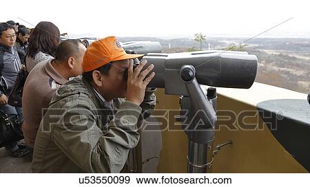 A man looks through telescope at the Imjingak peace park in Paju near the demilitarized zone (DMZ) View Large Photo Image Stock Photo - A man looks through telescope at the Imjingak peace park in Paju near the demilitarized zone (DMZ). Fotosearch