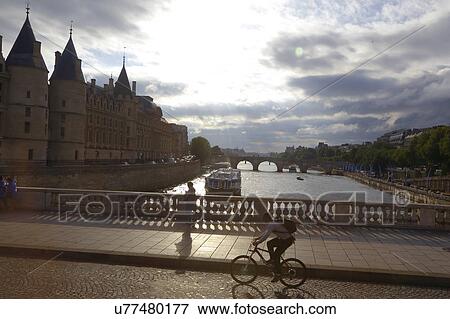 Stock Photo - A man rides a bicycle over the River Seine, in Paris, France. Fotosearch