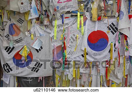 Barbed wire fence separates South from North Korea - South Korean flags and prayer wishes attached to fence for those separated or who had died during the Korean War View Large Photo Image Stock Photograph - Barbed wire fence separates South from North Korea - South Korean flags and prayer wishes attached to fence for those separated or who had died during the Korean War. Fotosearch