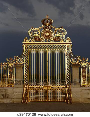 Stock Photograph - Golden entry gates of Chateau De Versailles with setting sunlight, France. Fotosearch