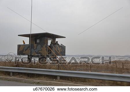 Stock Photograph - Lookout tower and Barbed wire fence separates South from North Korea - Asia. Fotosearch