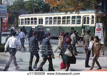 Stock Photo - Residents of Seoul South Korea walk in front of preserved old traincar - Seoul South Korea. Fotosearch