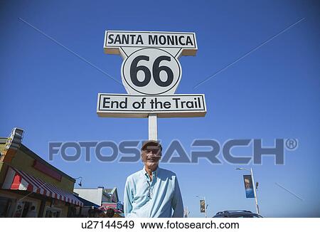 Stock Photo - Santa Monica, California, USA 5/2/2015, Route 66 sign and photographer Joe Sohm at Santa Monica Pier, end of famous Route 66 highway from Chicago. Fotosearch