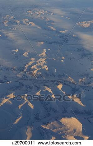 Stock Image - Snowy mountains of Canada from 30, 000 feet - aerial view. Fotosearch