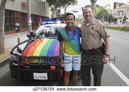 Picture - West Hollywood, Los Angeles, California, USA, June 14, 2015, 40th annual Gay Pride Parade for LGBT Community, down Santa Monica Blvd., LA Police Dept. with Rainbow LGBT flag on car poses with gay male. Fotosearch