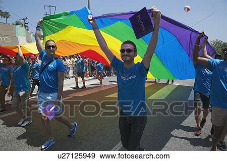Stock Photo - West Hollywood, Los Angeles, California, USA, June 14, 2015, 40th annual Gay Pride Parade for LGBT Community, down Santa Monica Blvd., men flying gay rainbow flag. Fotosearch