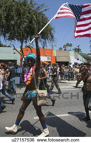 Stock Photograph - West Hollywood, Los Angeles, California, USA, June 14, 2015, 40th annual Gay Pride Parade for LGBT Community, down Santa Monica Blvd., gay black man in bikini raises US Flag. Fotosearch