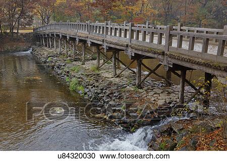 Stock Image - Wood bridge and Autumn color at Namsangol traditional folk village, Seoul, South Korea. Fotosearch