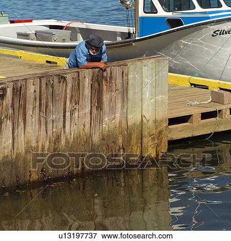 Man standing leaning over a pier in Prince Edward Island, Canada View Large Photo Image Stock Photo - Man standing leaning over a pier in Prince Edward Island, Canada. Fotosearch
