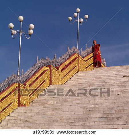 Stock Photography - Monk standing on staircase at Golden Rock. Fotosearch