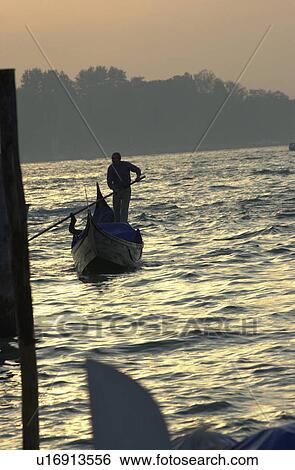 Oarsmen driving a gondola during sunset in Venice, Italy View Large Photo Image Stock Photograph - Oarsmen driving a gondola during sunset in Venice, Italy. Fotosearch
