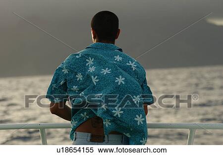 Stock Photography - Rear of a young man on a boat watching the sea, Moorea, Tahiti, French Polynesia, South Pacific. Fotosearch