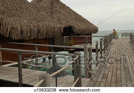 Stock Photo - Thatched roof wooden structures supported by stilts in the sea, Moorea, Tahiti, French Polynesia, South Pacific. Fotosearch