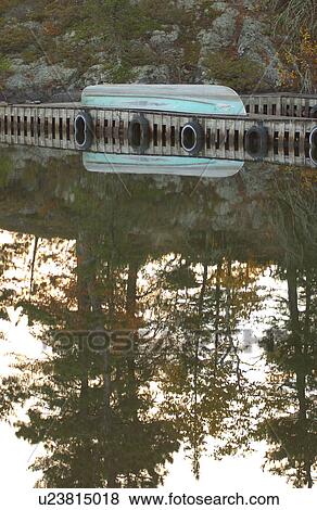 Stock Photo - Upside Down Canoe on Boat Dock Reflected in Lake. Fotosearch