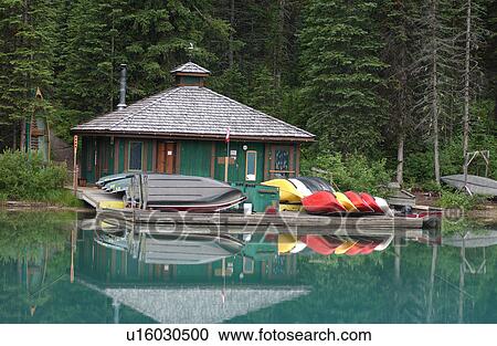 Stock Image - View of boats on a pier near a boathouse on a lake Rocky Mountains, Canada. Fotosearch