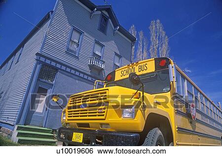 Stock Photograph - A school bus parked in front of an old building. Fotosearch