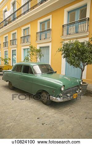 Stock Image - Russian car in Old Havana, Cuba with yellow building in background. Fotosearch