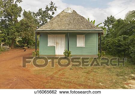 Stock Image - Small green house with thatched roof in central Cuba. Fotosearch